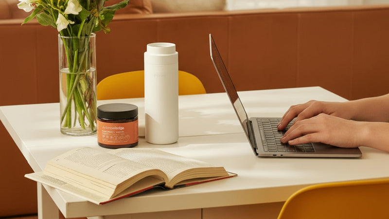 A view of a man working on a design project at his desk with laptop and sketches.