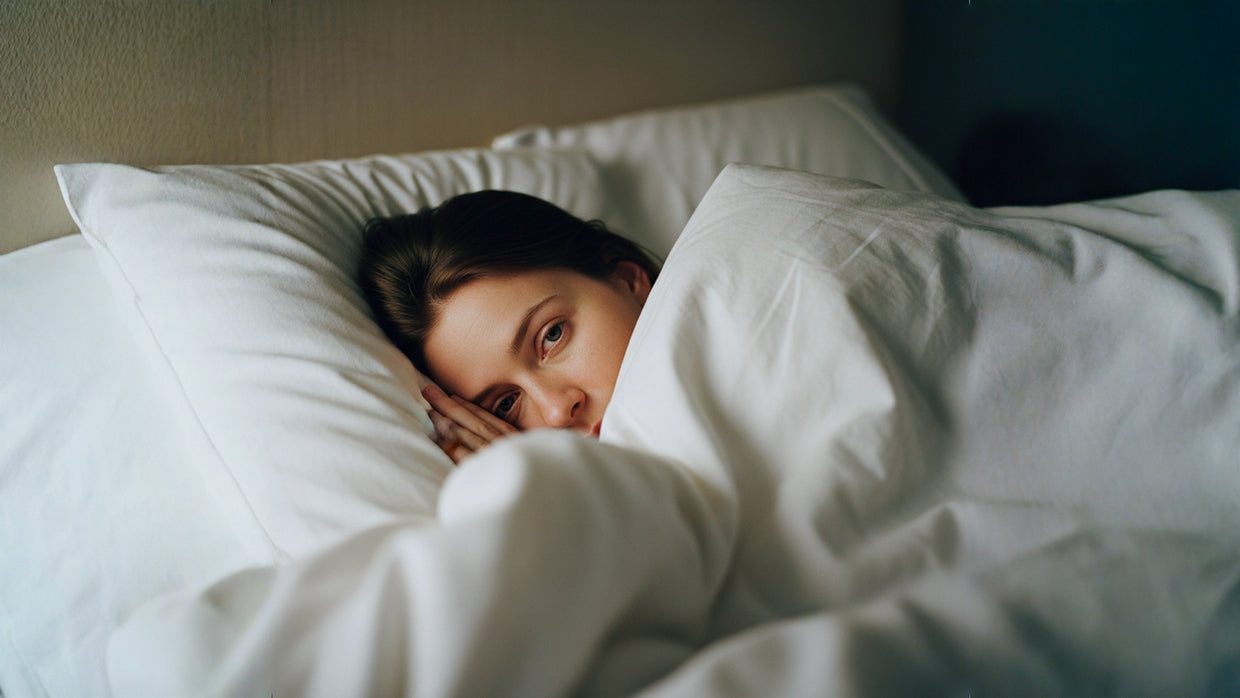 A woman with a sad face laying down in her bed.