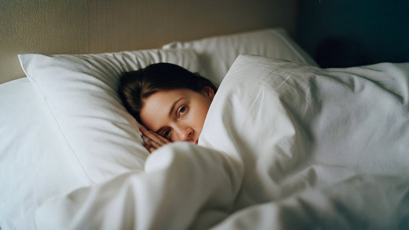 A woman with a sad face laying down in her bed.