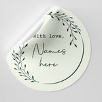 Round white sticker with black text and leaf design on a light gray background